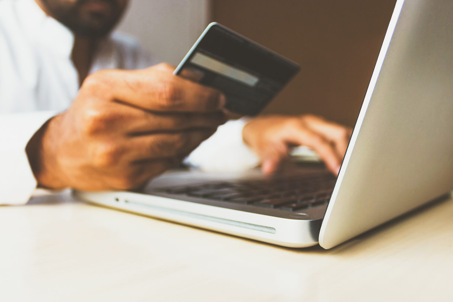 Person using laptop holding a credit card.